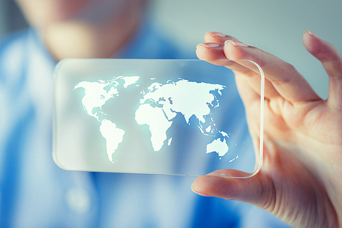 business, technology, international communication, mass media and people concept - close up of woman hand holding and showing transparent smartphone with world map on screen