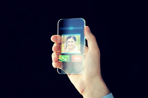 business, future technology, communication and people concept - close up of male hand holding and showing transparent smartphone with incoming video call icon on screen over black background
