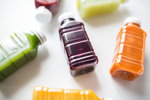 healthy eating, drinks, diet and detox concept - close up of plastic bottles with different fruit or vegetable juices on white