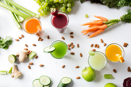 healthy eating, drinks,  and detox concept - close up of glasses with different fruit or vegetable juices and food on table
