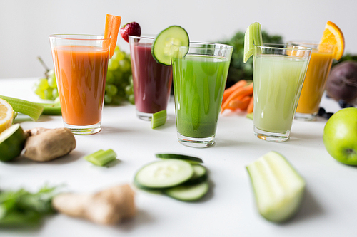 healthy eating, drinks, diet and detox concept - glasses with different fruit or vegetable juices and food on table