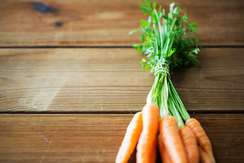 healthy eating, food, dieting and vegetarian concept - close up of carrot bunch on wooden table