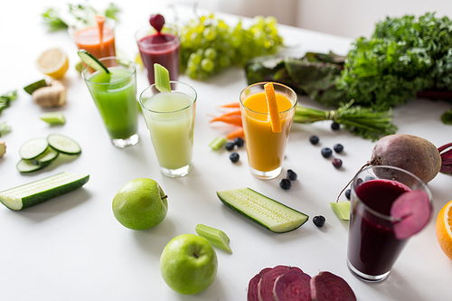 healthy eating, drinks, diet and detox concept - glasses with different fruit or vegetable juices and food on table