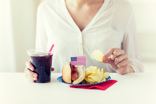 american 독립기념일, celebration, patriotism and holidays concept - close up of woman eating potato chips with hot dog and cola in plastic cup on 4th july at home party