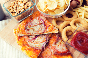 fast food and unhealthy eating concept - close up of pizza and other snacks on wooden table