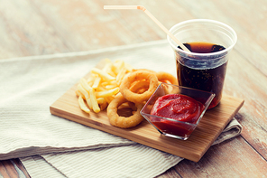 fast food and unhealthy eating concept - close up of deep-fried squid rings, french fries, cola and ketchup on wooden table