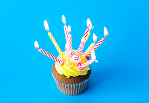 holiday, celebration, greeting and party concept - birthday cupcake with many burning candles over blue background