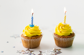 holiday, celebration, greeting and party concept - birthday cupcakes with burning candles