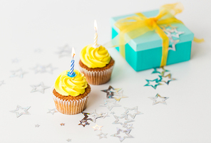 holiday, celebration, greeting and party concept - birthday cupcakes with burning candles and present