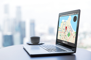 technology, location, navigation, business and modern life concept- close up of open laptop computer with gps navigator map on screen and coffee cup on table at office or hotel room