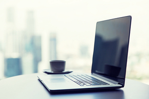 technology, business and modern life concept- close up of open laptop computer and coffee cup on table at office or hotel room