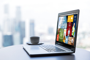 technology, internet, media, business and modern life concept- close up of open laptop computer with news web page on screen and coffee cup on table at office or hotel room