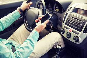 transport, business trip, technology and people concept - close up of young man with smartphone driving car