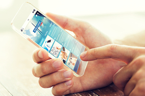 business, mass media, information, technology and people concept - close up of male hand holding and showing transparent smartphone with world news web page