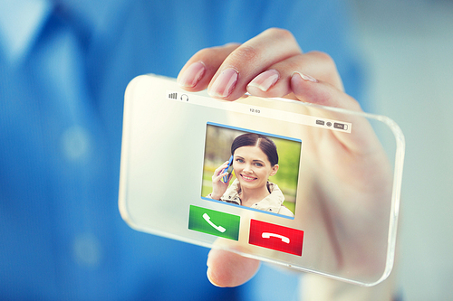business, technology, communication and people concept - close up of woman hand holding and showing incoming call on transparent smartphone screen