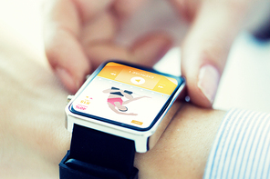 sport, fitness, technology and people concept - close up of woman hands setting smart watch with sports application on screen