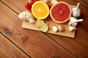 traditional medicine, cooking, food and ethnoscience concept - citrus fruits, ginger and garlic on wooden background
