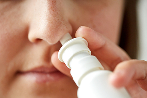 healthcare, flu, rhinitis, medicine and people concept - close up of sick woman using nasal spray