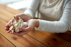 health, people, food, traditional medicine and ethnoscience concept - woman hands holding garlic for cooking or healing