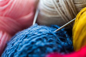 handicraft and needlework concept - close up of knitting needles and balls of yarn
