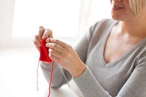 people and needlework concept - woman hands knitting with needles and red yarn