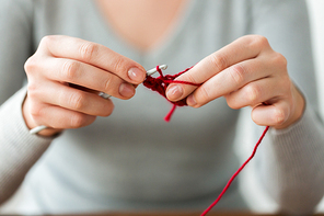 people and needlework concept - woman hands knitting with crochet hook and red yarn