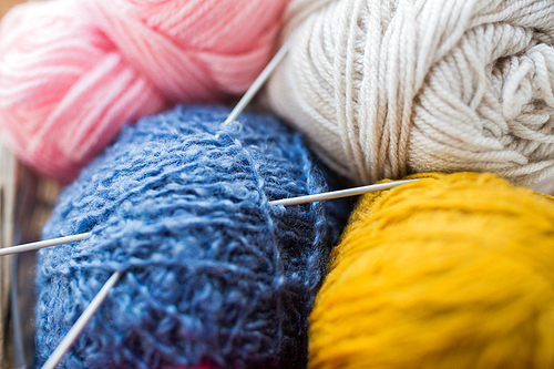 handicraft and needlework concept - close up of knitting needles and balls of yarn