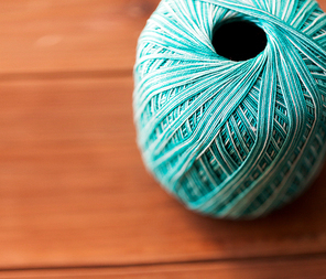 handicraft , knitting and needlework concept - close up of turquoise cotton yarn ball on wood