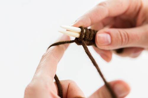 people and needlework concept - close up of woman hands knitting with needles and brown yarn