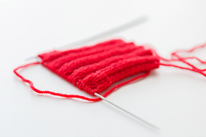 handicraft and needlework concept - hand-knitted item with knitting needles