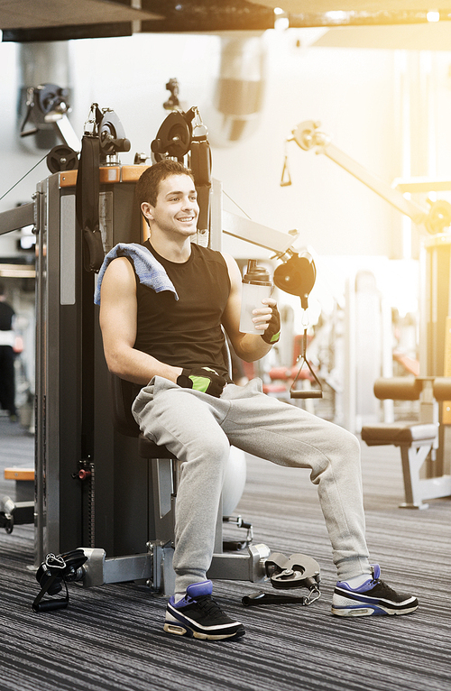 sport, fitness, equipment, lifestyle and people concept - smiling man exercising on gym machine