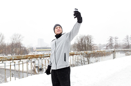 fitness, sport, people, exercising and healthy lifestyle concept - young man taking selfie with smartphone in winter
