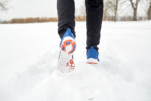 fitness, sport, people, footwear and healthy lifestyle concept - close up of male feet running along winter road and snow