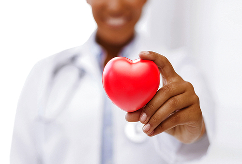 health, medicine and charity concept - close up of african american female doctor hands holding red heart