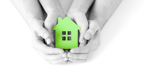 real estate and family home concept - closeup picture of male and female hands holding green blank paper house