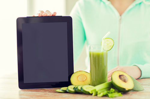 healthy eating, technology, diet and people concept - close up of woman hands with tablet pc, green fresh juice and vegetables sitting at table