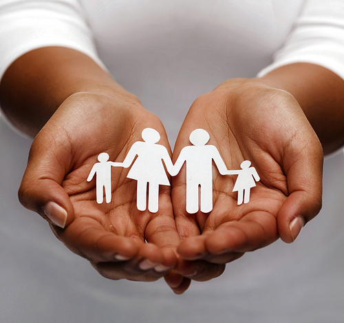 life insurance, love and charity concept - closeup of womans cupped hands showing paper man family