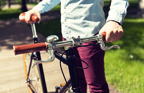 people, style, leisure and lifestyle - close up of young hipster man with fixed gear bike on city street