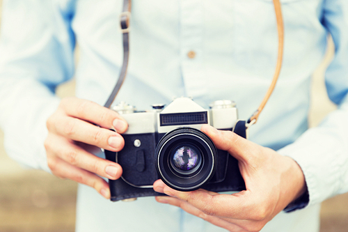 people, photography, technology, leisure and lifestyle - close up of young hipster man with retro vintage film camera on city street