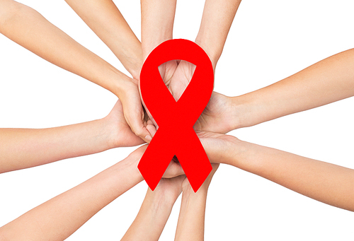 healthcare, charity, people and medicine concept - close up of hands with red aids and hiv awareness ribbon over white background