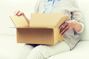 age, delivery, mail, shipping and people concept - close up of senior woman looking into open parcel box at home