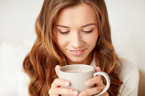 leisure, drink, winter and people concept - close up of happy young woman with cup of coffee at home