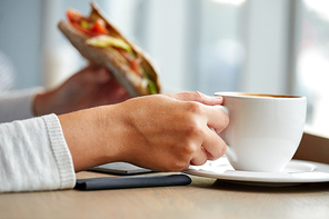 food, dinner and people concept - woman drinking coffee and eating panini sandwich for breakfast or lunch at cafe
