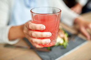 food, drink, eating and people concept - hand of woman with glass of juice and salad at restaurant