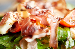 food, dinner, haute cuisine and eating concept - close up of prosciutto ham salad