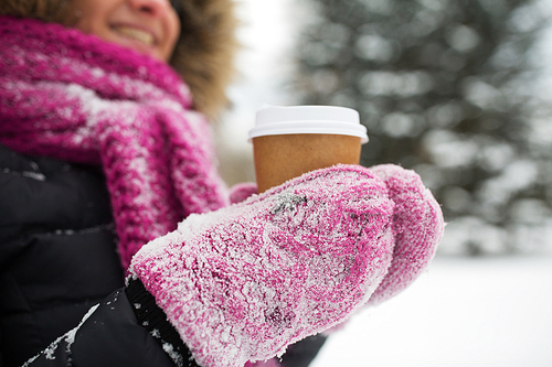 people, season, drinks and leisure concept - close up of woman hand with coffee cup outdoors in winter