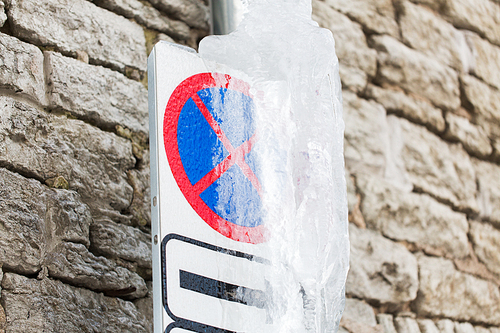 season, traffic and winter concept - iced no stopping road sign over wall