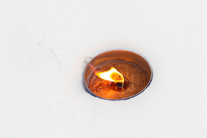 winter holidays and christmas concept - outdoor candle burning on snow