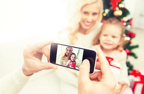 family, christmas, technology and people concept - close up of man taking picture of his family by smatrphone