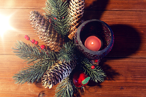 christmas, decoration, holidays and new year concept - close up of natural fir branch decoration and fir-cone and candle in lantern on wooden table